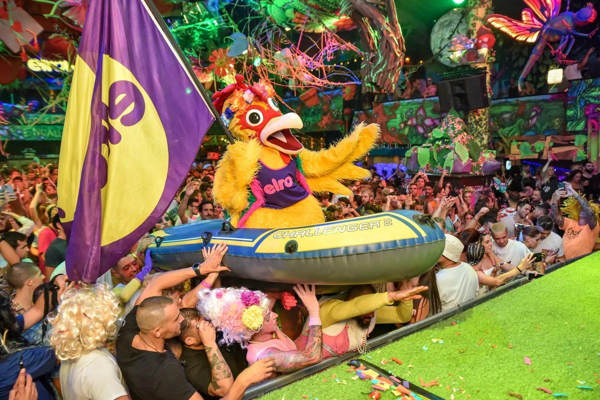 Mascota de elrow sobre una barca hinchable sostenida por el público