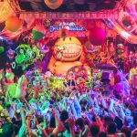 Público bailando en una fiesta de elrow bajo una decoración de figuras gigantes