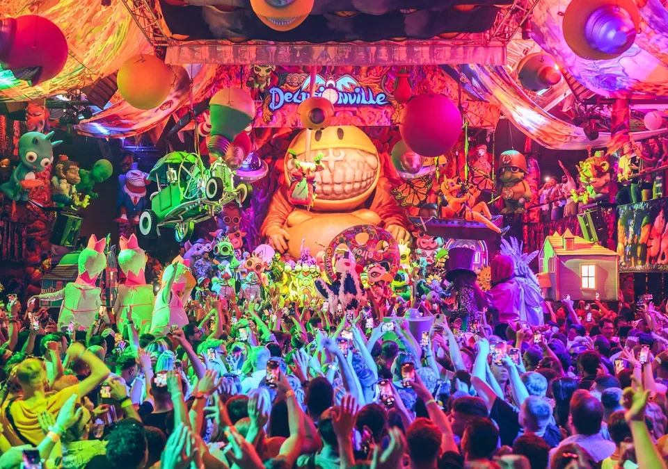Público bailando en una fiesta de elrow bajo una decoración de figuras gigantes