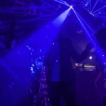 Pista de club iluminada con láseres azules y gente bailando