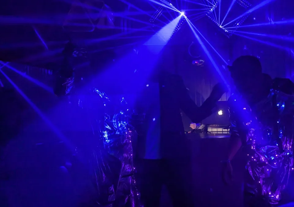 Pista de club iluminada con láseres azules y gente bailando